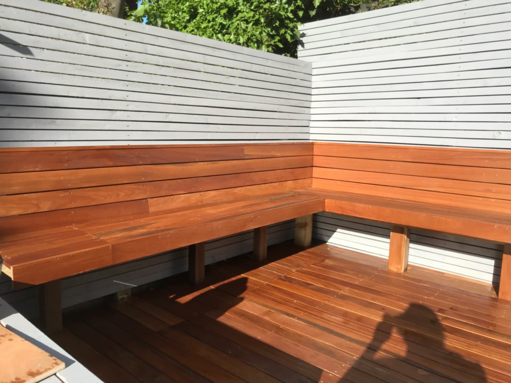 Pale grey horizontal slatted fencing we built in a Bounds Green garden, behind a built-in hardwood corner bench