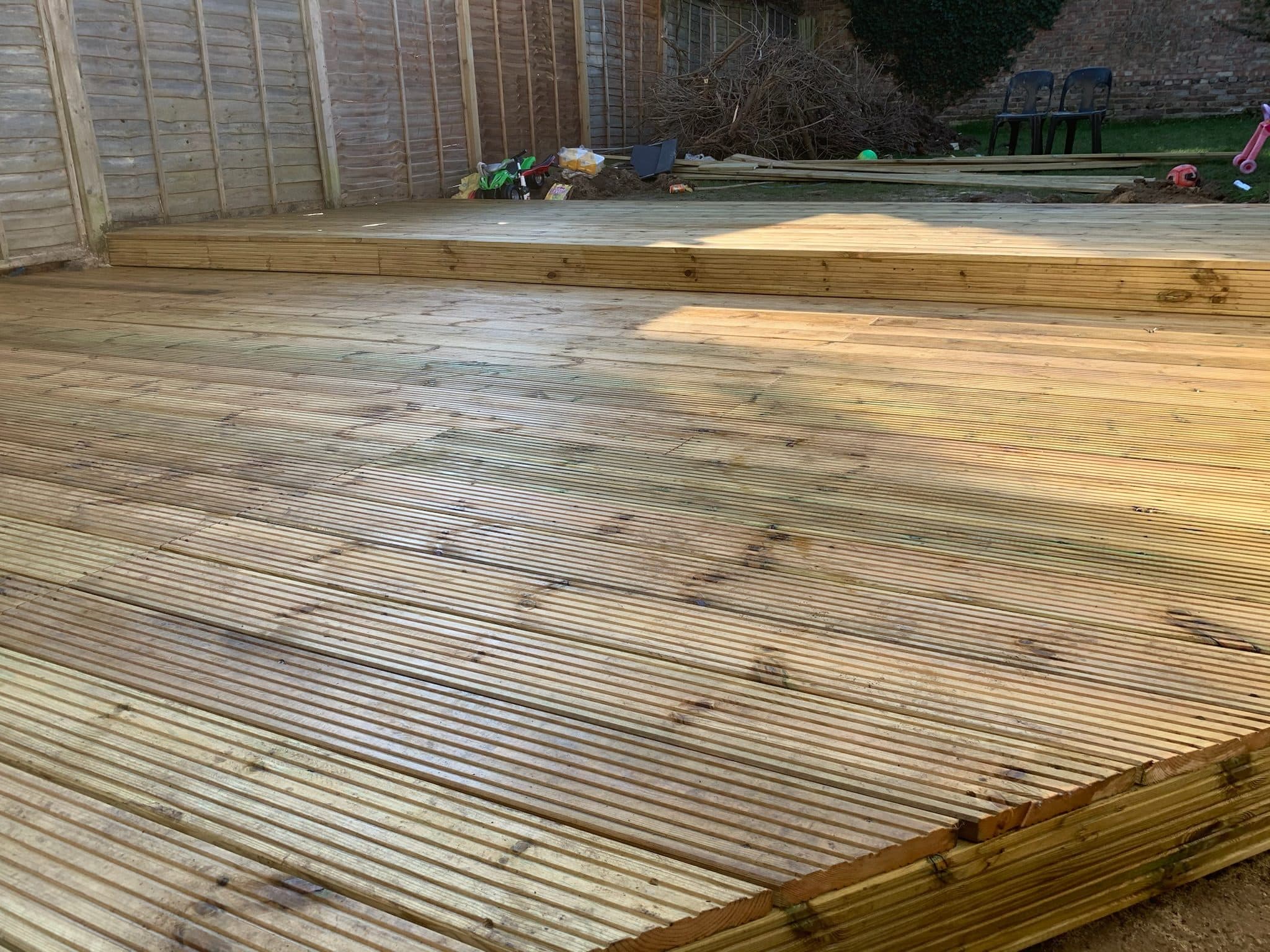 The finished hardwood deck filling the back garden of a Golders Green semi-detached, stepping straight out of the French doors and running to the boundary